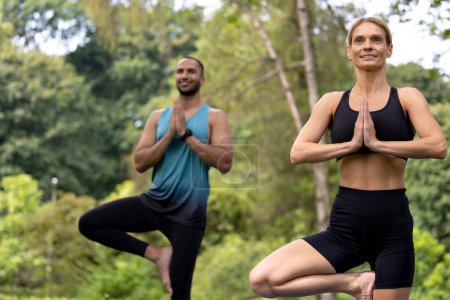 Foto de Naturaleza en forma. Amo Asana. Relajación. Hombre y mujer haciendo ejercicios de yoga en el parque verde. - Imagen libre de derechos
