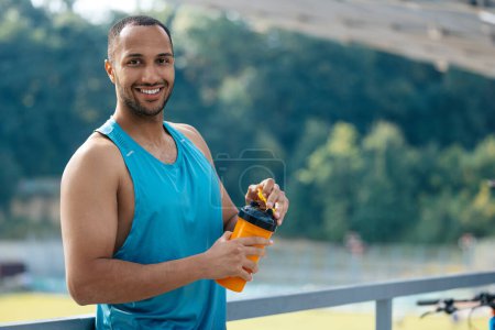 Photo for Athlete. Smiling handsome athlete with no spill cup in hands - Royalty Free Image
