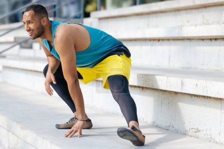 Téléchargez les photos : Jambes tendues. Jeune homme en tenue de sport faisant de l'exercice et des jambes tendues - en image libre de droit