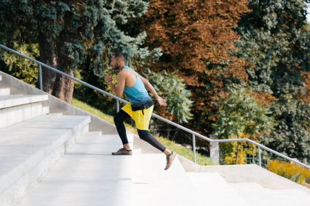 Foto de Ejercicio al aire libre. Atleta de piel oscura haciendo ejercicio en las escaleras - Imagen libre de derechos