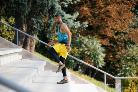 Foto de Haciendo ejercicio. Atleta de piel oscura bien parecido haciendo ejercicio en las escaleras - Imagen libre de derechos