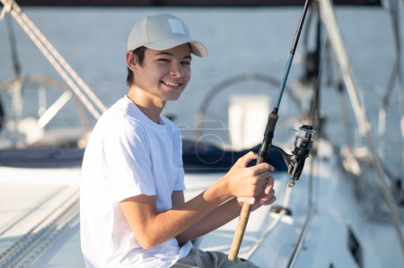 Téléchargez les photos : Sur un yacht. Sourire adolescent dans une casquette sur un yacht - en image libre de droit
