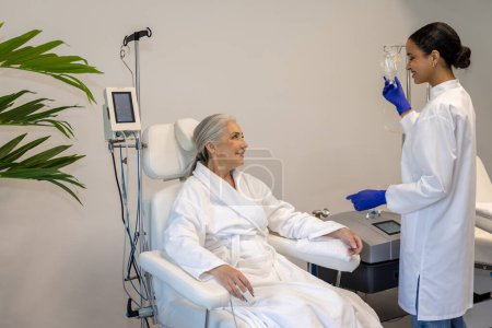 Téléchargez les photos : Médecin professionnel faisant perfusion IV pour la patiente âgée en clinique de beauté. - en image libre de droit