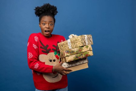 Foto de Mujer joven en jersey rojo con venado navideño sosteniendo cajas de regalo - Imagen libre de derechos