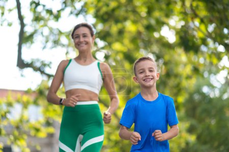 Téléchargez les photos : Jogging ensemble. Femme et son fils jogging dans le parc et l'air satisfait - en image libre de droit