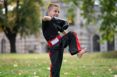 Foto de Boxeo. Niño de pelo rubio con guantes de boxeo haciendo ejercicio en el parque - Imagen libre de derechos