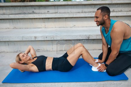 Téléchargez les photos : Muscles abdominaux d'entraînement féminin sportif avec le soutien de son ami. - en image libre de droit