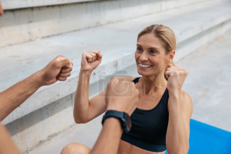 Photo for Two friends man and woman working out together and doing some crunches outdoors, clenched fists, celebrating success. - Royalty Free Image