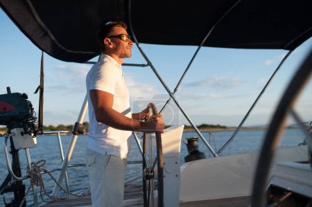 Téléchargez les photos : Un homme sur un yacht. Homme mûr confiant aux cheveux courts naviguant sur un yacht - en image libre de droit