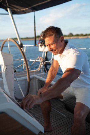 Foto de En un yate. Hombre con ropa blanca navegando en un yate - Imagen libre de derechos