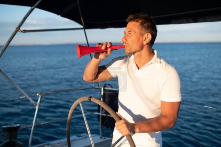 Téléchargez les photos : Homme au mégaphone. Homme en t-shirt blanc sur un yacht avec un mégaphone à la main - en image libre de droit