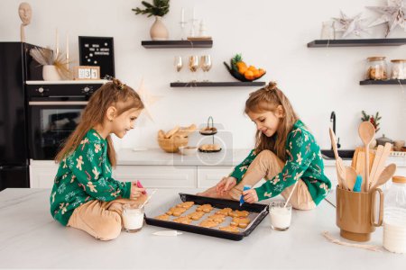 Téléchargez les photos : Enfants préparant des biscuits au gingembre pour le Père Noël et regardant impliqué - en image libre de droit
