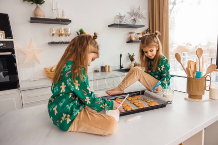 Téléchargez les photos : Cheveux longs mignon enfant assis sur la table et la préparation de biscuits au gingembre - en image libre de droit