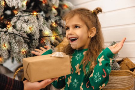 Foto de Dulce niña sosteniendo una caja de regalo en las manos y mirando anticipado - Imagen libre de derechos
