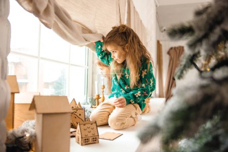 Foto de Chica de pelo largo preparando un regalo de Navidad y buscando involucrado - Imagen libre de derechos
