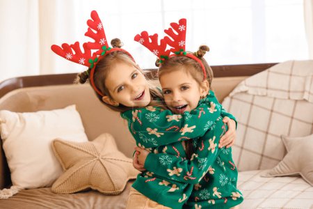Photo for Sweet little girls in green sweaters and with deer horns on heads - Royalty Free Image