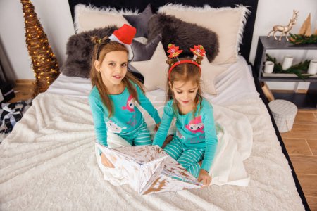 Foto de Adorables gemelos en sombreros de Navidad jugando en la cama - Imagen libre de derechos
