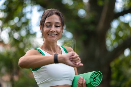 Téléchargez les photos : Le sport dans le parc. Femme brune en tenue de sport prête à faire de l'exercice dans le parc - en image libre de droit