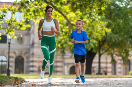 Photo for Jogging together. Woman and her son jogging in the park and looking contented - Royalty Free Image