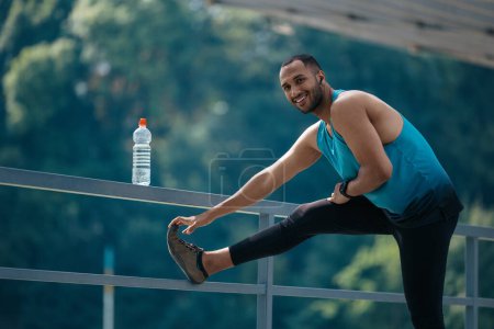Photo for Legs stretching. Dark-haired man in sportswear exercising and stretching his legs - Royalty Free Image
