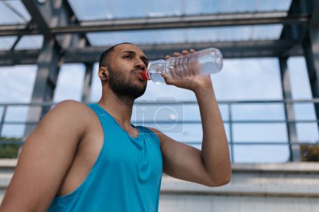 Photo for After workout. Well-built handsome sportsman drinking water after workout - Royalty Free Image