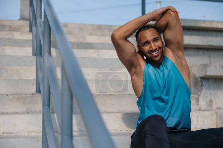 Photo for Exercising. Dark-skinned athlete stretching his arms and looking contented - Royalty Free Image