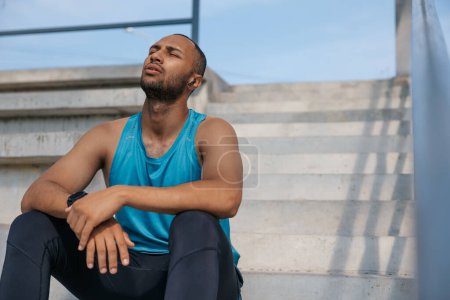 Photo for After workout. Young man in sportswear on the stairs after a good workout - Royalty Free Image