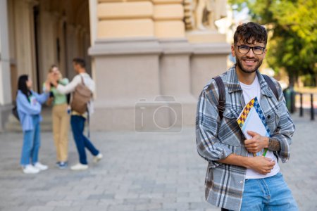 Foto de Estudiante. Joven con anteojos y camisa a cuadros en el patio de la universidad - Imagen libre de derechos