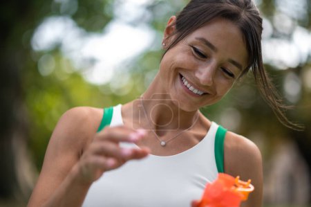 Téléchargez les photos : Après l'entraînement. Sourire jeune femme avec une bouteille dans la main se sentir bien après l'entraînement - en image libre de droit