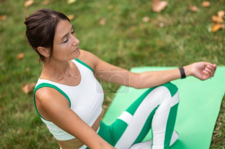 Foto de Meditación. Mujer en ropa deportiva verde sentada en una pose de loto y meditando - Imagen libre de derechos