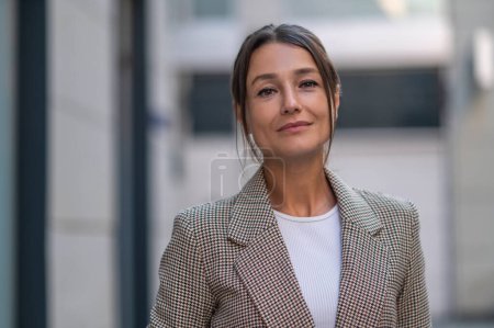 Photo for Confident woman wearing beige suit posing near urban building. - Royalty Free Image