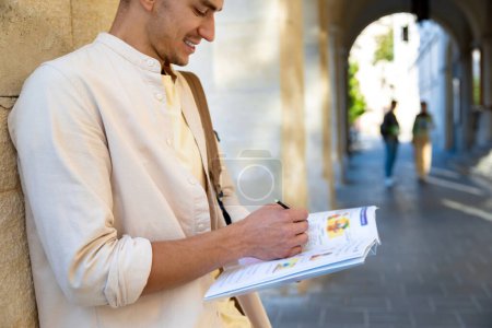 Photo for Student. Handsome young man standing near the wall with a textbook in hands - Royalty Free Image
