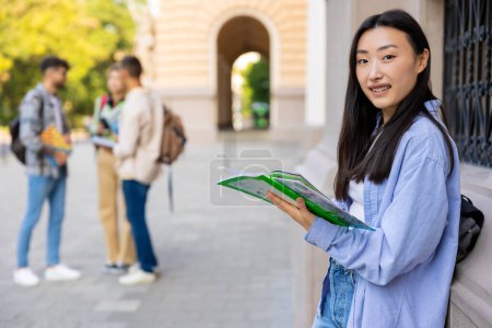 Photo for Asian student. Asian long-haired girl with a notebook in the college yard - Royalty Free Image