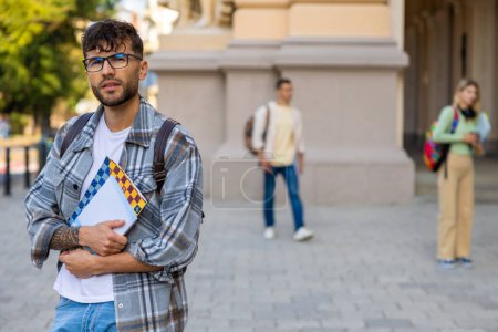 Foto de Estudiante. Joven con anteojos y camisa a cuadros en el patio de la universidad - Imagen libre de derechos