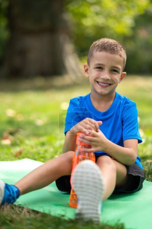 Photo for Water balance. Cute boy in blue tshirt with orange bottle in hands - Royalty Free Image