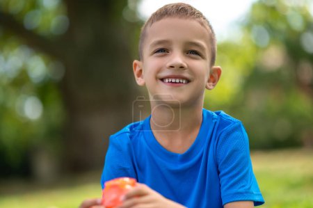 Photo for Good mood. Cute boy of school age in blue tshirt looking contented - Royalty Free Image