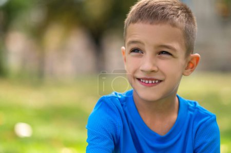 Photo for Good mood. Cute boy of school age in blue tshirt looking contented - Royalty Free Image