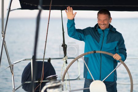 Téléchargez les photos : Capitaine. Homme mûr souriant naviguant sur un bateau - en image libre de droit