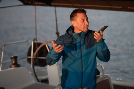 Photo for On the call. Man on the yacht with a phone in hands - Royalty Free Image