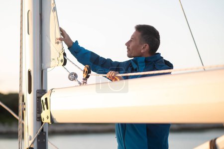 Téléchargez les photos : L'homme sur le yacht. Homme mûr naviguant sur le yacht et regardant occupé - en image libre de droit
