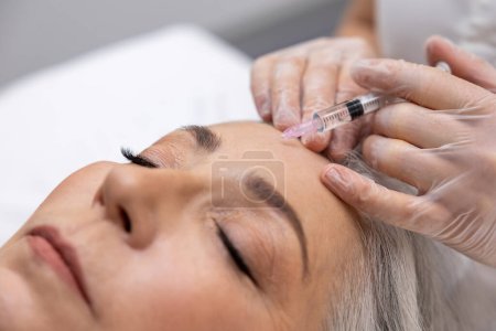 Photo for Filler injections. Beautician doing filler injections to a mature female patient - Royalty Free Image