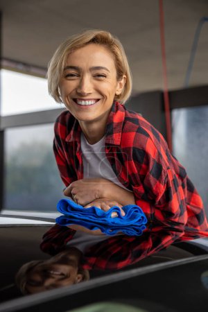 Photo for Car service. Young smiling woman cleaning the car and feeling good - Royalty Free Image