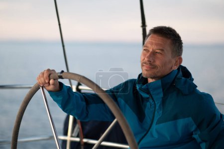 Téléchargez les photos : Sur le yacht. Beau homme mature naviguant sur un yacht et regardant confiant - en image libre de droit