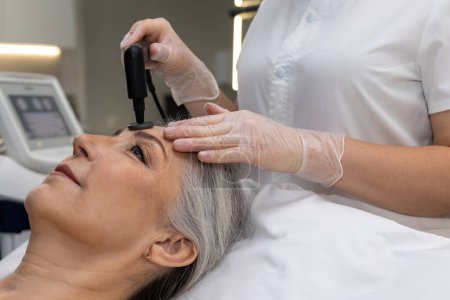 Photo for Laser procedures. Beautician doing laser beauty procedures to a woman - Royalty Free Image