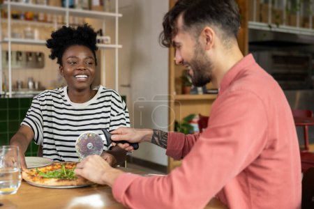 Téléchargez les photos : Jeune couple ayant pizza dans un café et regardant apprécié - en image libre de droit