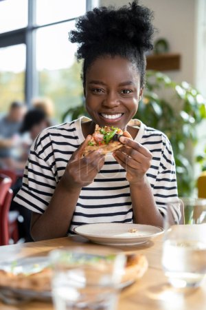 Photo for Cute dark-skinned young woman enjoying pizza - Royalty Free Image