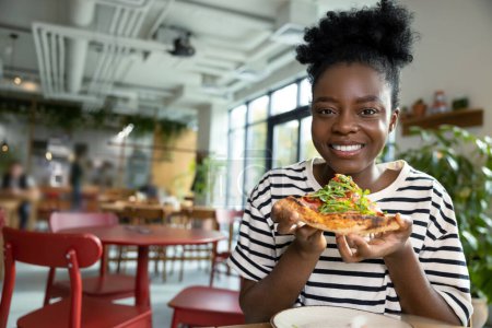 Photo for Pretty young dark-skinned woman eating pizza and feeling good - Royalty Free Image