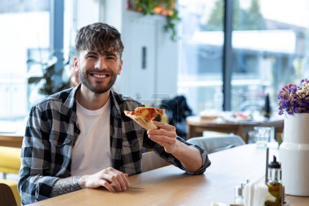 Foto de Sonriente joven buscando disfrutado mientras come pizza - Imagen libre de derechos