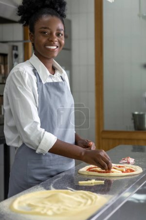 Foto de Mujer de piel oscura preparando masa para pizza - Imagen libre de derechos