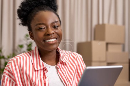 Foto de Atractiva mujer negra usando tableta digital para el trabajo en línea en casa. - Imagen libre de derechos
